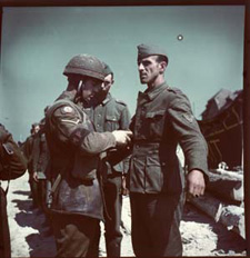 Photo montrant un militaire canadien fouillant des prisonniers allemands, vers juin 1944.