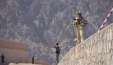Un membre des Forces canadiennes affect  l'quipe provinciale de reconstruction de Kandahar est en sentinelle avec la Police nationale afghane prs d'un poste subordonn de la ville de Kandahar.